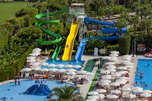 Ein wundervolles Resort mit Wasserrutschen und Pools, umgeben von Palmen und vielen Liegestühlen.