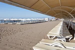Strand mit Sonnenliegen unter Sonnenschirmen im Miracle Resort