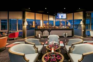 Lounge-Bereich im Miracle Resort mit Bar, Fernseher, Sesseln und Tisch mit Blumendekor.