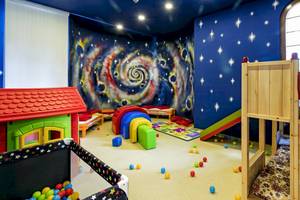Kinderzimmer im Miracle Resort mit Galaxie-Thema, bunten Spielzeugen und Spielhaus.
