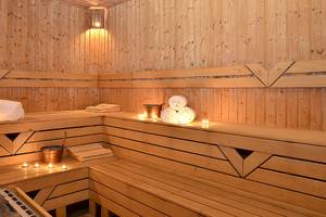 Sauna im Miracle Resort mit Holzbänken, Kerzen und Handtüchern.