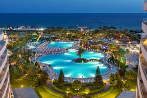 Abendliche Ansicht des Miracle Resort mit Swimmingpool und Palmen.