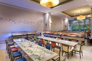 Innenansicht des Speisesaals im Miracle Resort mit langen Tischen, bunten Stühlen und Dekor an der Wand.