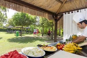 Mann im Miracle Resort, der auf der Terrasse ein Frühstück vorbereitet