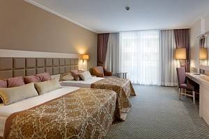 Doppelzimmer im Miracle Resort mit zwei Betten, Schreibtisch, Stühlen und Fernseher.