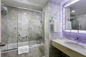 Badezimmer im Miracle Resort mit Badewanne, Dusche und Waschbecken.