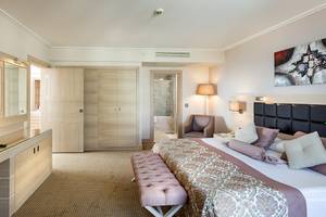 Interieur eines Schlafzimmers im Miracle Resort Hotel mit Bett, Fernseher und Möbeln.