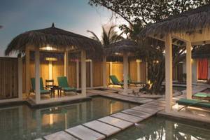 Außenbereich des Oblu Nature Hengeli mit Swimmingpool und Lounge-Gebieten unter Strohdächern.