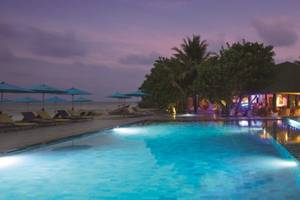 Pool im OBLU NATURE Helengeli Hotel mit Loungeliegen und beleuchteten Bäumen in der Nacht