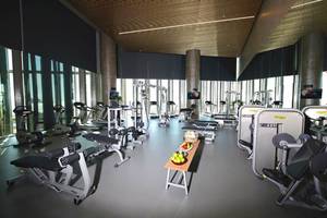 Fitnessstudio im Rixos Premium Dubai JBR mit verschiedenen Trainingsgeräten und einer Tafel mit Früchten.