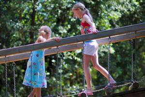 Zwei Maedchen auf einer Holz-Haengebruecke im Freizeitpark
