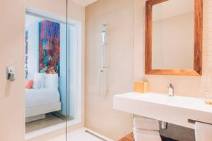 Badezimmer im Coral Level at Iberostar Selection Cancun Hotel mit Glasdusche und offenem Bett