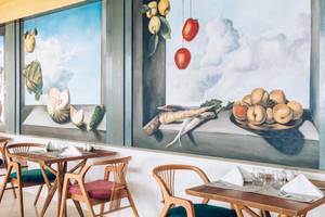Restaurant-Innenbereich im Coral Level at Iberostar Selection Cancun mit kunstvollen Wandgemälden und gekleideten Tischen.