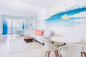Wohnzimmer im Coral Level at Iberostar Selection Cancun mit weißen Möbeln und blauer Wandgestaltung.