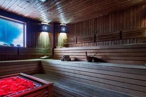 Eine leere Sauna mit Holzbänken und einem roten Feuerkorb im Crystal Family Resort & Spa.