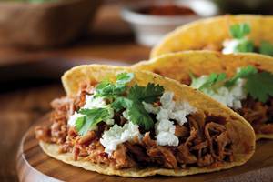 Ein Taco mit Rinderfleisch und Feta auf einer Holzplatte.