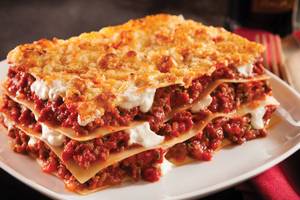 Eine Portion Lasagne mit Tomatensoße und Käse auf einem weißen Teller, serviert im Crystal Family Resort & Spa.