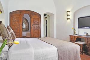 Schlafzimmer im Mövenpick Resort Sharm el Sheikh mit Doppelbett, Holzschrank und Fernseher