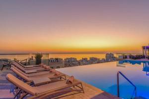 Dachterrasse des AX The Palace Hotels mit Swimmingpool und Blick auf die Stadt und den Ozean.