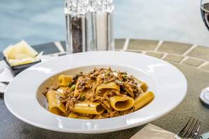 Ein Teller mit Penne in einer braunen Soße, serviert im AX The Palace Hotel.