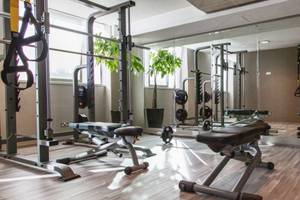 Fitnesscenter im AX The Palace Hotel mit verschiedenen Trainingsgeräten und Spiegeln.