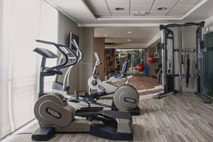 Fitnesscenter im AX The Palace Hotel mit Laufbändern, Ellipsentrainern und Hantelbank.