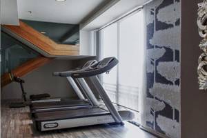 Fitnessraum im AX The Palace Hotel mit zwei Laufbändern und einer Treppe im Hintergrund.
