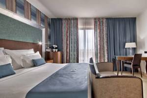 Suite-Zimmer im AX The Palace Hotel mit Bett, Schreibtisch und Sesseln.