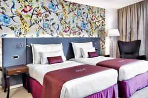 Doppelzimmer im AX The Palace mit zwei Betten und blumiger Tapete.