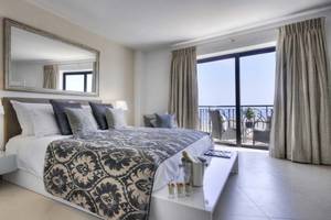 Schlafzimmer im AX The Palace Hotel mit einem großen Bett, vielen Kissen, und einem Balkon mit Meerblick.