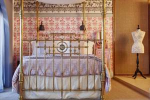 Schlafzimmer im AX The Palace Hotel mit einem viktorianischen Bett und rosa Tapeten.