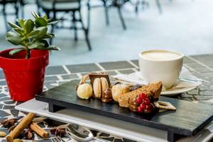 Dessertplatte mit verschiedenen Leckereien, Kaffee und einer Pflanze im AX The Palace