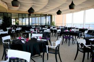 Innenansicht des Restaurants im AX The Palace Hotel mit vielen gedeckten Tischen und Meerblick.