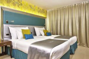 Zimmer im AX The Palace Hotel mit zwei Betten, blauen Kopfkissen und cremefarbenen Laken.