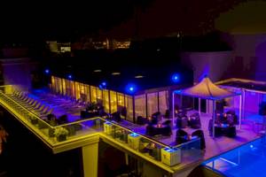 Nachtansicht der Dachterrasse des AX The Palace Hotels mit blauen Beleuchtung und Swimmingpool