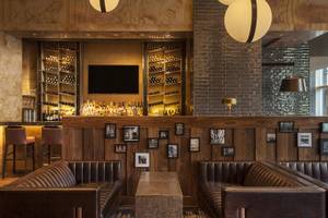 Innenansicht der Bar im Westin New York at Times Square Hotel mit Barhockern, Ledersofas und einer Bartheken mit Fernseher.