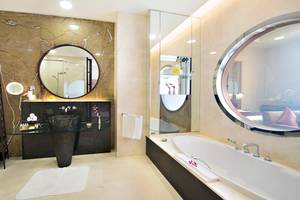 Badezimmer im Al Raha Beach Hotel mit Badewanne, Spiegeln und Waschbecken.