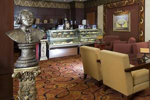 Hotellobby mit Büste und Möbeln, darunter Sessel, Tisch und Sofas.