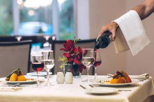 Ein Restauranttisch im Iberostar Mehari Djerba mit einem Gast, der Wein einschenkt.