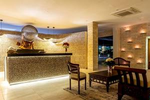 Lobby des Royal Zanzibar Beach Resorts mit goldenem Empfangstresen, Skulptur, Blumen und Möbeln.