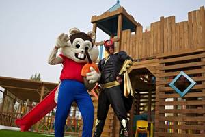 Zwei Maskottchen vor einem hölzernen Spielplatz im Rixos Hotel