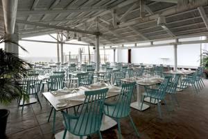 Innenansicht des Restaurants des Playabonita Hotels mit türkisfarbenen Stühlen und Tischen.