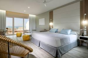 Innenansicht eines Schlafzimmers im Playabonita Hotel mit einem großen Bett und Blick auf das Meer.
