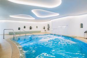 Ein Hallenbad im Iberostar Selection Fuerteventura Palace mit Wasserfall und modernen Beleuchtungselementen.