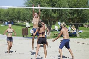 Beachvolleyballspiel im Atlantica Aegean Blue Resort mit Spielern auf Sand und einer Frau im Vordergrund.
