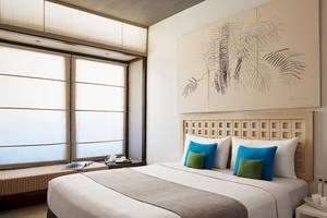 Innenansicht eines Hotelzimmers von Jetwing Blue mit großem Bett, Kunstwerk an der Wand und Fenstern.