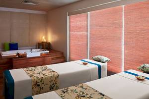 Spa-Behandlungsraum im Jetwing Blue mit zwei Betten, Badewanne und orangefarbenen Rolläden.