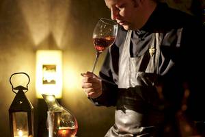 Mann der Sofitel Marrakech Lounge & Spa Wein kostet in einem dunklen Raum