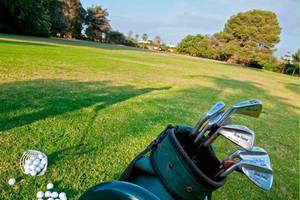 Golfplatz mit einem Golfbag, Schlägern und Bällen auf dem Rasen.