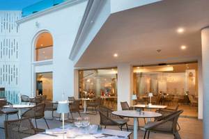 Terrasse des Guayarmina Princess Hotels mit Tischen, Stühlen und Palmen im Hintergrund